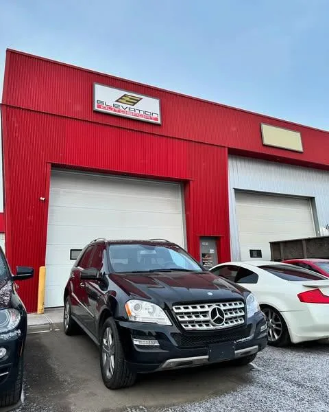 A black SUV is parked in front of a red building with large garage doors