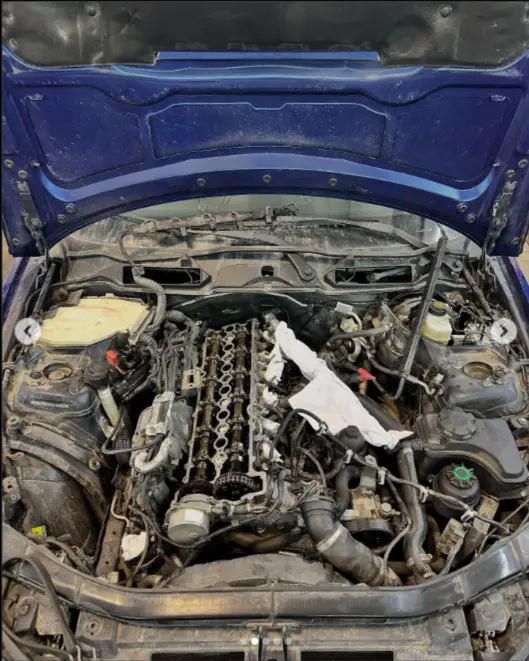 A car engine is exposed and disassembled, revealing various mechanical components